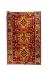 Alfombra rectangular de estilo geométrico tribal en tonos rojo, naranja, dorado y gris, con tres grandes medallones centrales y guardas laterales multicolor.