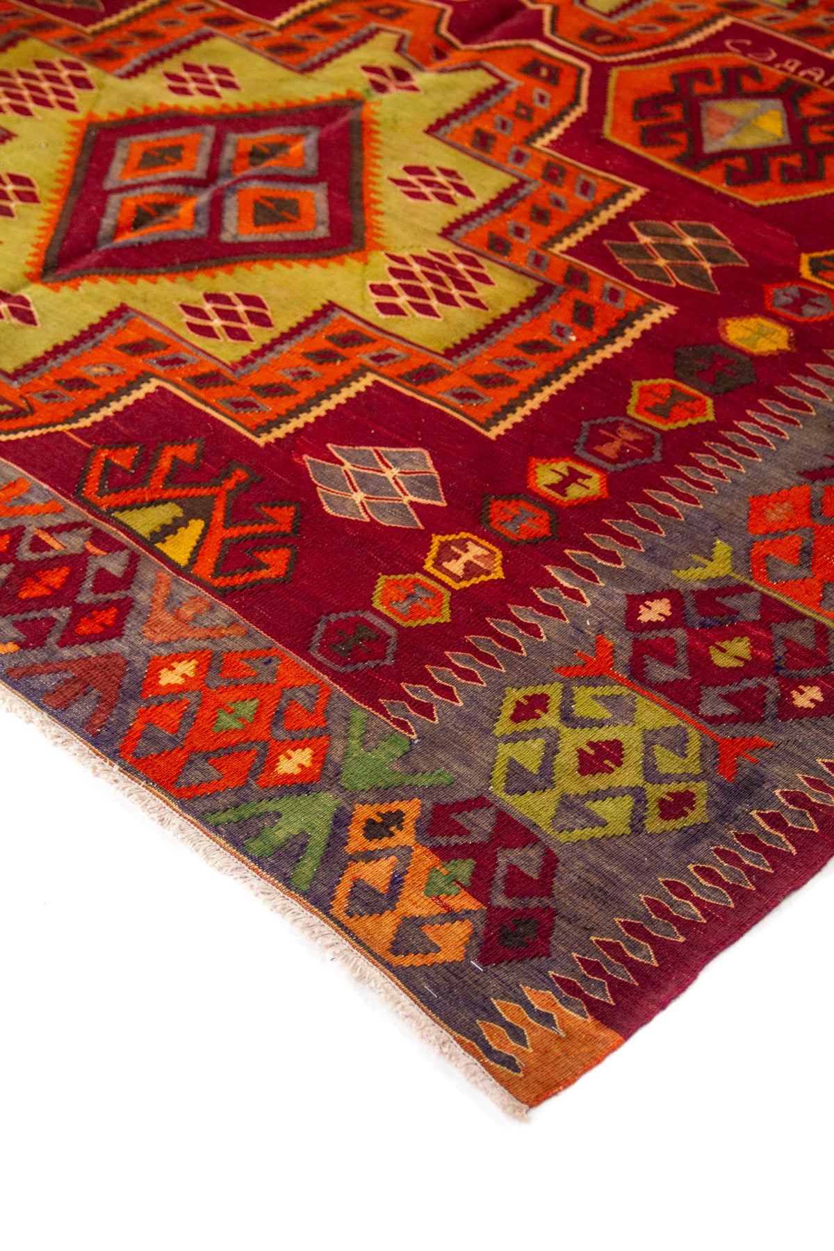 Acercamiento al diseño central de alfombra con patrones escalonados y figuras geométricas en rojo, naranja, dorado y gris.