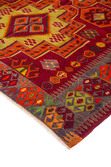 Acercamiento al diseño central de alfombra con patrones escalonados y figuras geométricas en rojo, naranja, dorado y gris.
