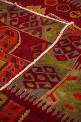Detalle de alfombra doblada que muestra la textura del tejido y la composición geométrica del borde en tonos cálidos 