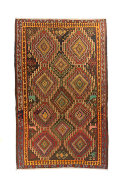 Alfombra artesanal rectangular en tonos rojo, dorado, verde y marrón con grandes rombos geométricos y guarda decorativa tribal