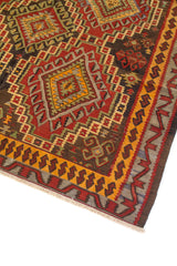 Primer plano de alfombra vintage con motivos geométricos tribales, rombos centrales y guarda decorativa en rojo, dorado y marrón