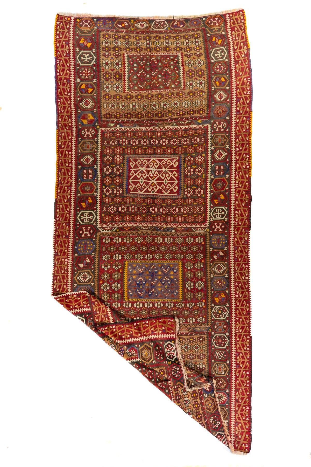 Alfombra artesanal geométrica vista en perspectiva con una esquina doblada que muestra su textura, tejido y reverso