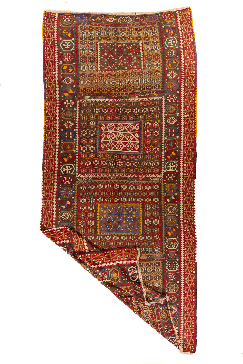 Alfombra artesanal geométrica vista en perspectiva con una esquina doblada que muestra su textura, tejido y reverso