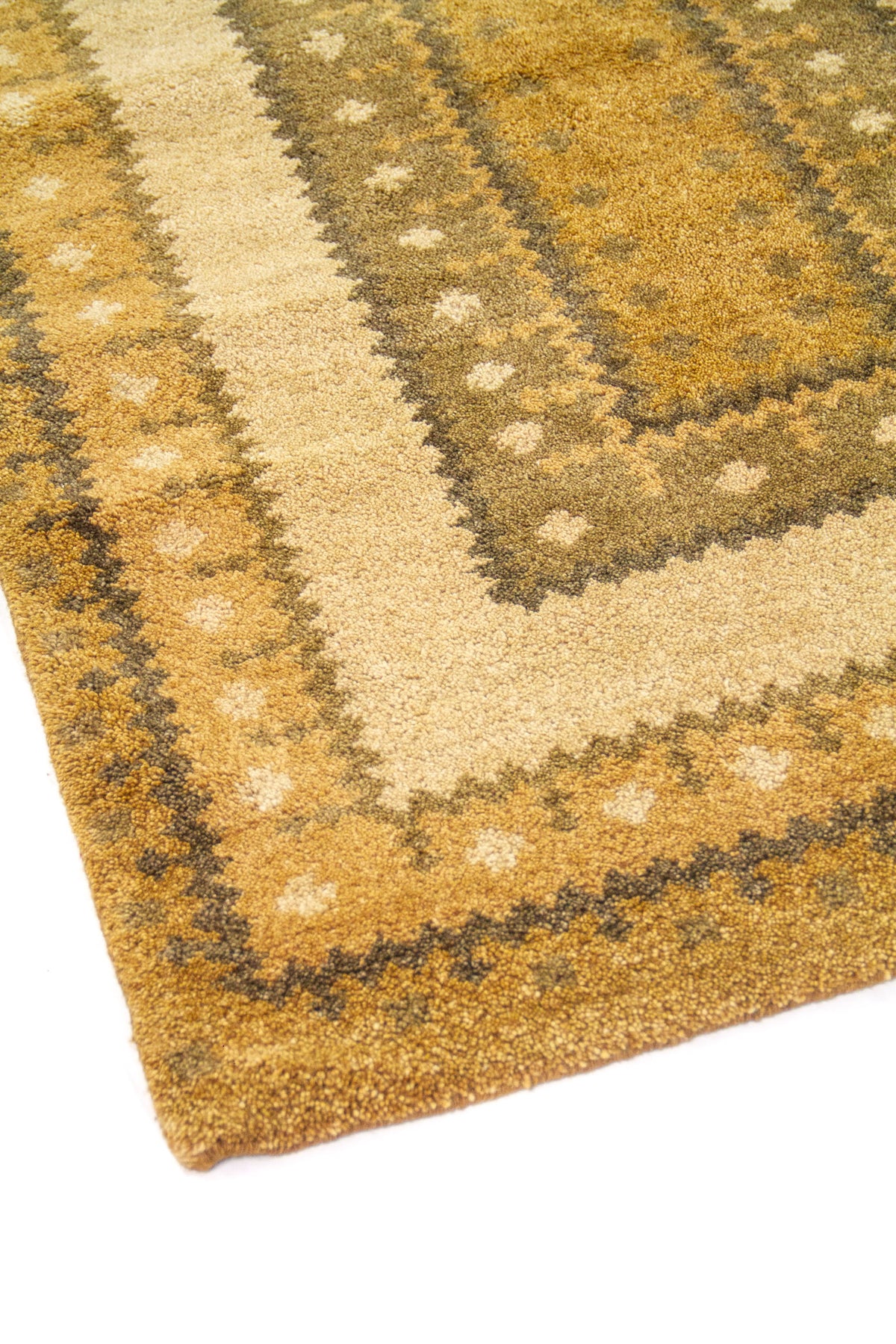 Detalle de esquina de alfombra dorado y beige con patrón geométrico escalonado y textura afelpada