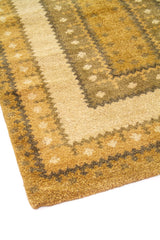 Detalle de esquina de alfombra dorado y beige con patrón geométrico escalonado y textura afelpada