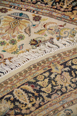 Detalle de alfombra doblada mostrando textura, reverso del tejido y composición decorativa en tonos beige, negro y dorado