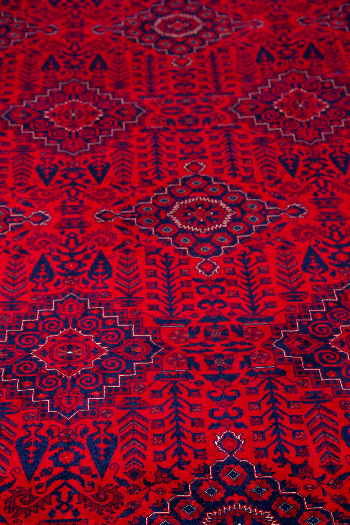 Detalle de textura de alfombra persa roja con medallones geométricos y motivos tribales