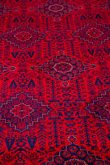 Detalle de textura de alfombra persa roja con medallones geométricos y motivos tribales