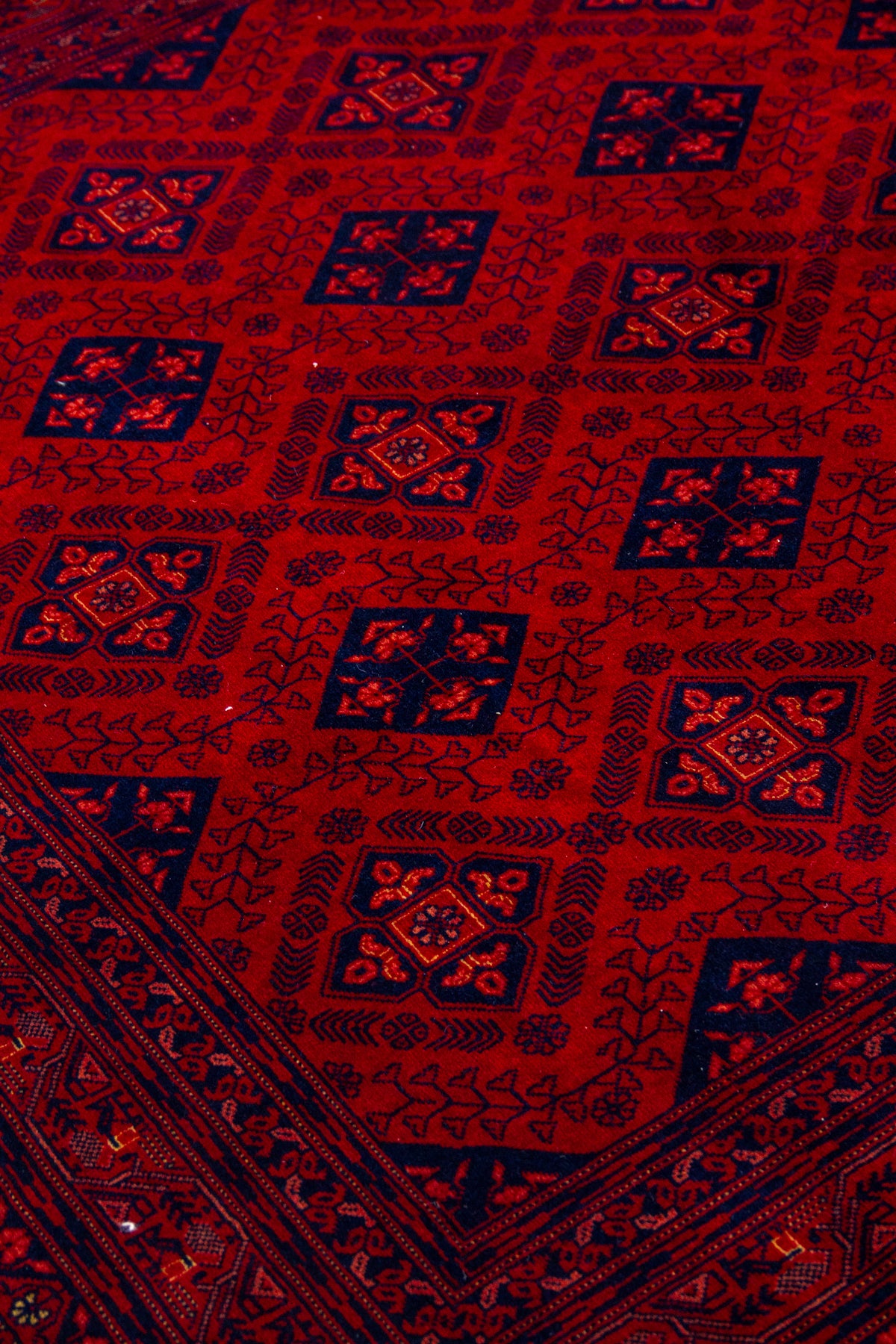 Detalle del diseño geométrico de alfombra Persa Afgan en tonos rojos y azul oscuro