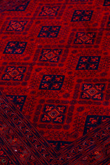 Detalle del diseño geométrico de alfombra Persa Afgan en tonos rojos y azul oscuro