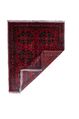 Alfombra Persa Afgan roja con esquina doblada mostrando reverso y flecos