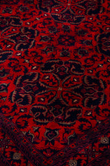 Detalle del diseño floral de alfombra Persa Afgan en tonos rojos y azul oscuro