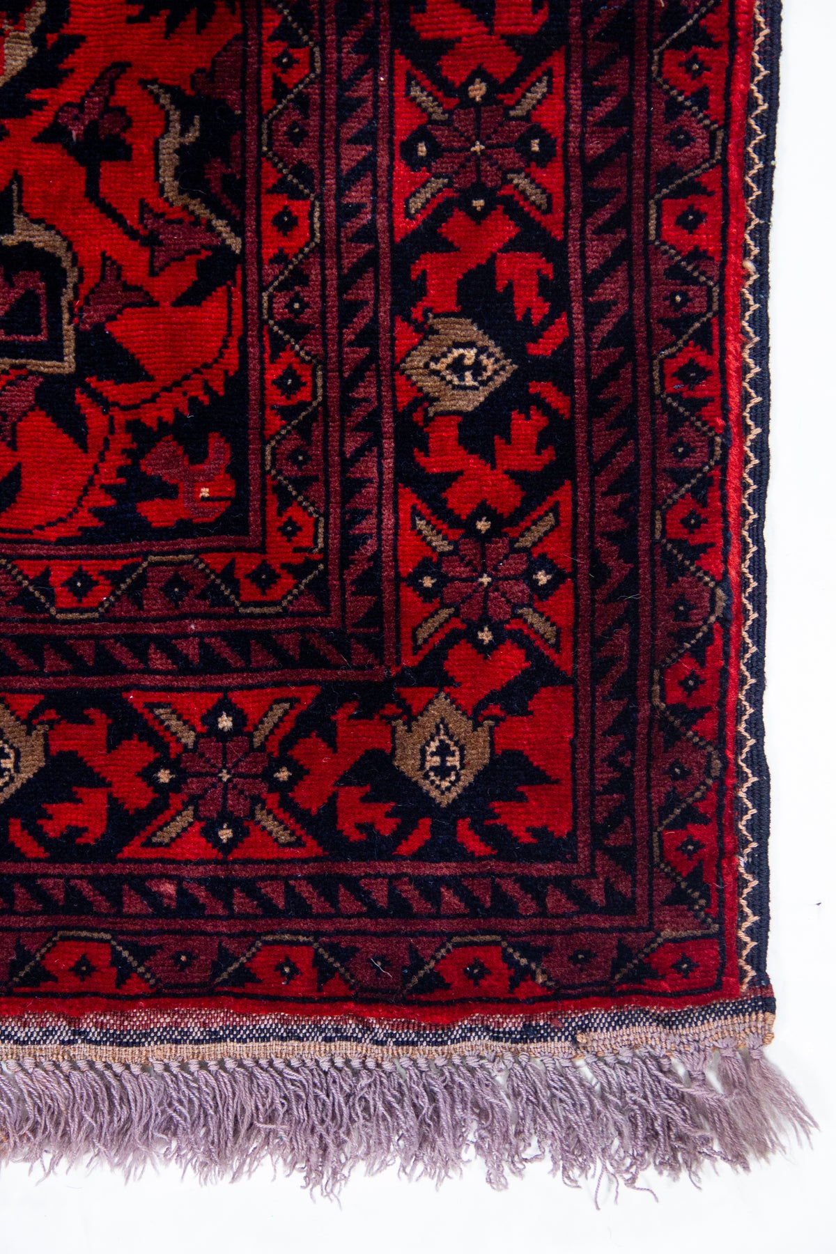 Detalle de guarda y flecos de alfombra Persa Afgan roja con motivos tradicionales