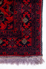Detalle de guarda y flecos de alfombra Persa Afgan roja con motivos tradicionales