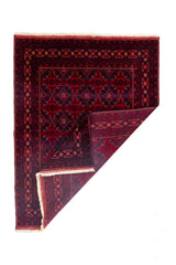 Alfombra Persa Afgan roja con esquina doblada mostrando reverso y flecos blancos