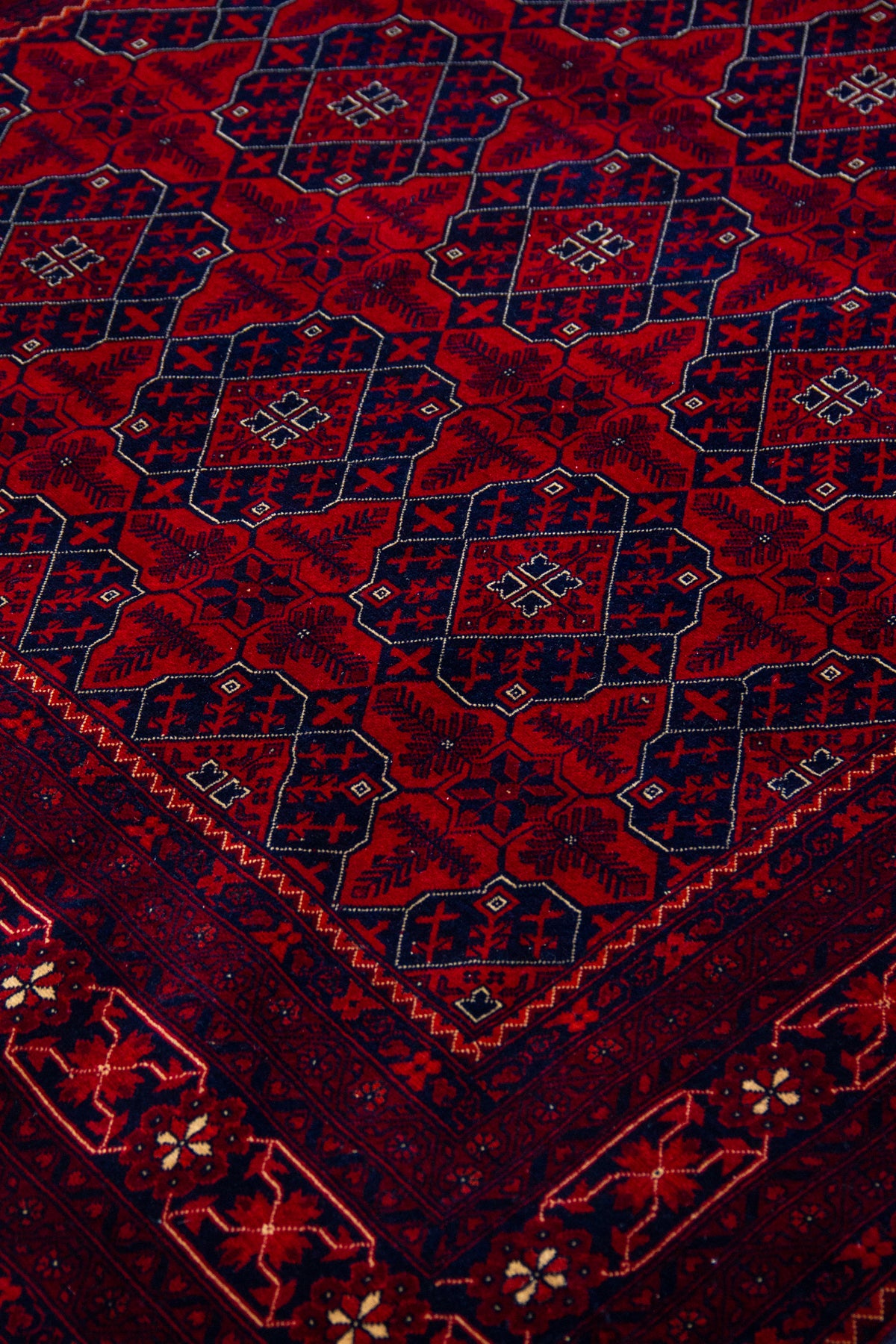 Detalle del diseño geométrico de alfombra Persa Afgan en tonos rojo y azul oscuro