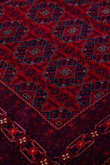 Detalle del diseño geométrico de alfombra Persa Afgan en tonos rojo y azul oscuro