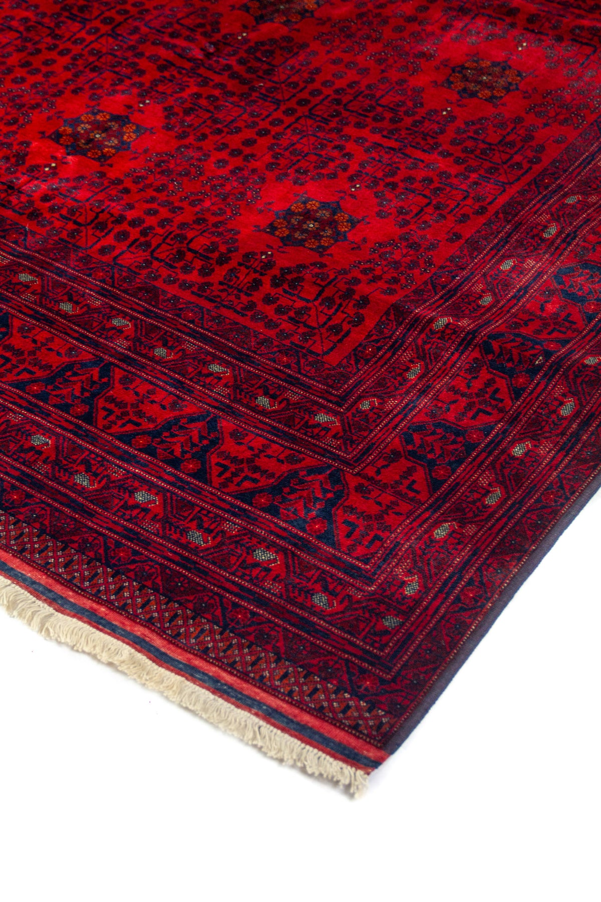 Primer plano de borde de alfombra oriental roja con diseño geométrico repetitivo, guardas decorativas y contraste en tonos rojo y azul marino.