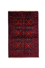 Alfombra de estilo geométrico con fondo rojo profundo, figuras simétricas en azul oscuro y detalles en tonos beige y rojo oscuro