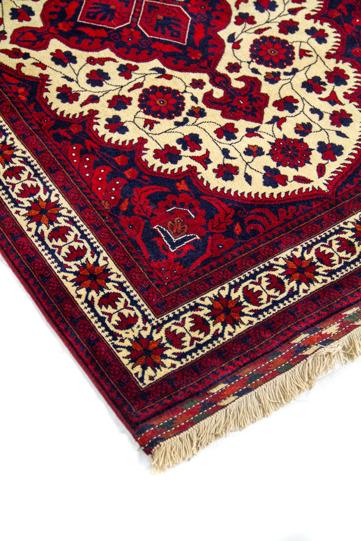 Primer plano de alfombra clásica con motivos florales y ornamentales sobre fondo amarillo claro , enmarcada por una guarda geométrica en tonos rojos y azul oscuro.