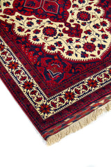 Primer plano de alfombra clásica con motivos florales y ornamentales sobre fondo amarillo claro , enmarcada por una guarda geométrica en tonos rojos y azul oscuro.