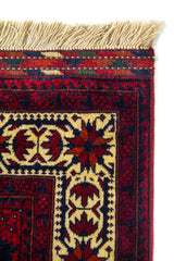Detalle del borde superior de una alfombra oriental con guarda amarillo claro decorada, flecos beige y combinación de colores rojo y azul.