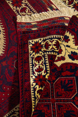 Detalle de alfombra doblada mostrando la textura del tejido, el reverso, los flecos y el contraste entre el campo central amarillo claro y los bordes rojos.