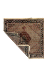 Alfombra oriental cuadrada con una esquina doblada que muestra el reverso, los flecos y el detalle del tejido