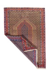 Alfombra clásica rectangular con una esquina doblada que muestra el reverso del tejido, los flecos y el detalle del borde geométrico