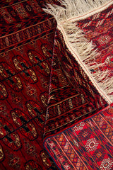 Detalle de textura y reverso de alfombra persa roja con flecos y diseño tradicional