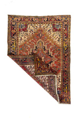 Alfombra rectangular de estilo oriental con una esquina doblada que muestra el reverso del tejido, los flecos y el detalle del borde geométrico