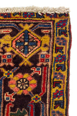 Detalle lateral de alfombra tribal con patrones geométricos, símbolos ornamentales y terminación con flecos beige