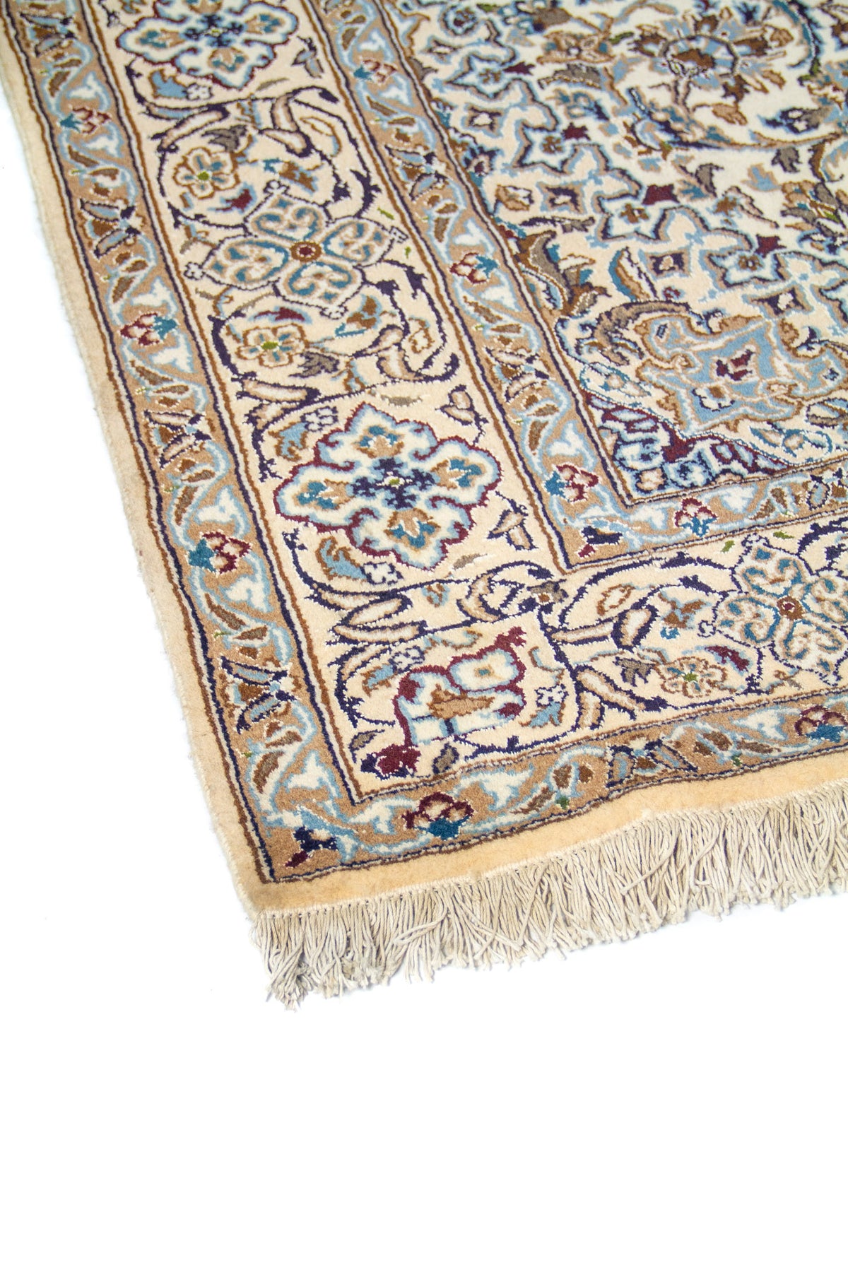 Primer plano de borde de alfombra oriental con guarda floral en tonos celeste, beige y azul sobre base blanco suave.