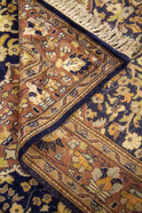 Detalle de alfombra doblada mostrando la textura del tejido, el reverso y los patrones florales del borde y campo central