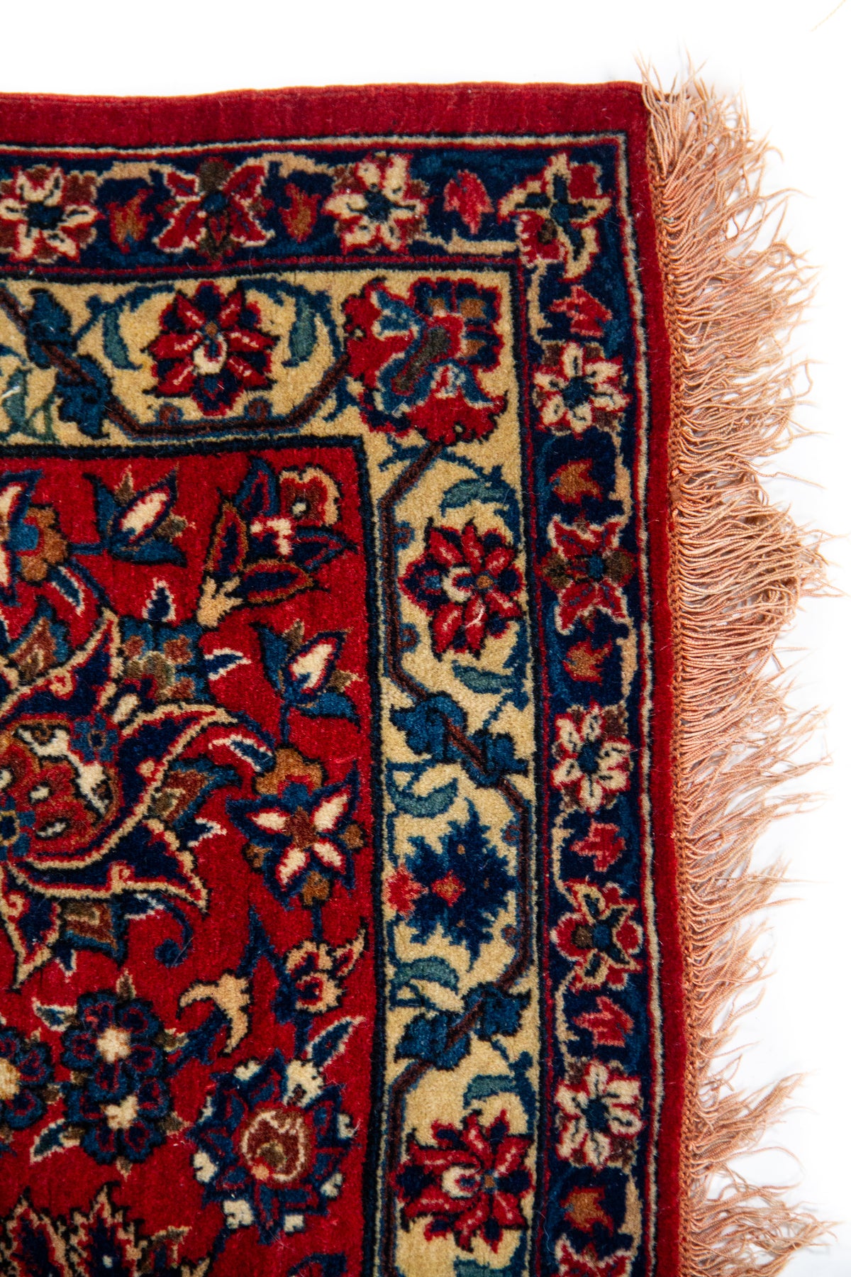 Detalle de flecos y borde de alfombra persa roja con motivos florales clásicos