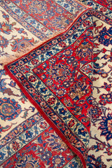 Detalle de textura y pliegue de alfombra persa con diseño floral en rojo, beige y azul