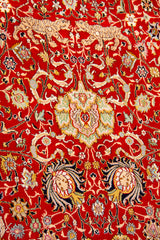 Detalle del diseño floral de alfombra persa roja con motivos ornamentales y figuras animales