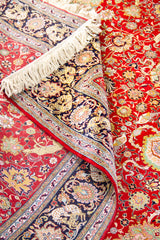 Detalle de textura y pliegue de alfombra persa roja con guarda oscura y diseño floral