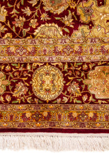 Detalle de guarda, flores y flecos de alfombra Persa Ispahan Seda en tonos rojo y dorado