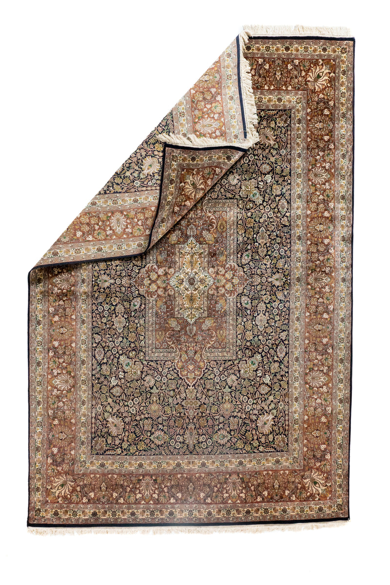 Alfombra Persa Ispahan Seda con esquina doblada mostrando reverso, flecos y guarda floral