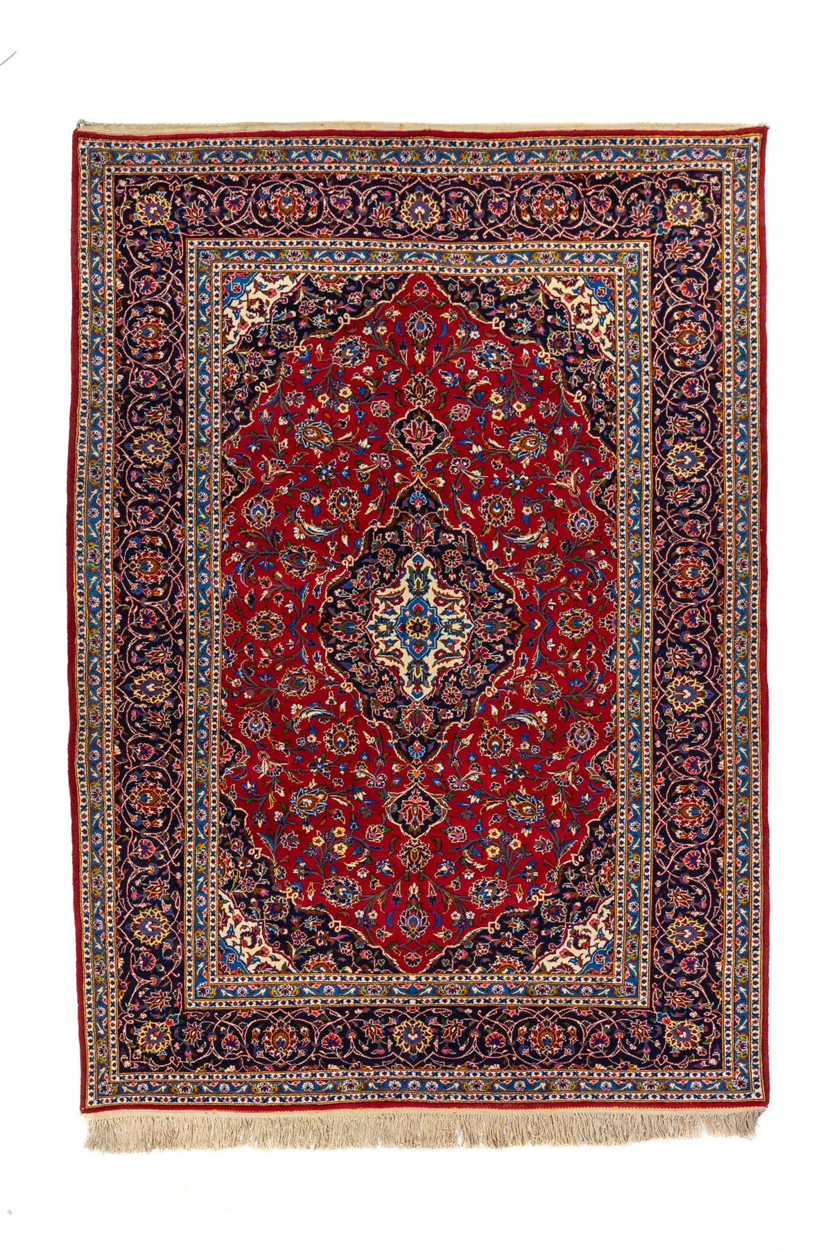 Alfombra oriental rectangular en tonos rojo intenso, azul oscuro y beige con medallón central floral y guarda decorativa clásica