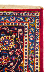 Detalle del borde de alfombra oriental con guarda azul marino, ornamentos florales y terminación con flecos beige