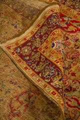Detalle de alfombra doblada mostrando textura, grosor, reverso del tejido y diseño floral clásico en tonos cálidos.