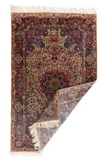 Alfombra persa rectangular doblada con flecos y diseño floral tradicional en tonos beige y azul