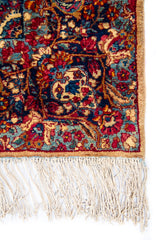 Detalle de guarda, textura y flecos de alfombra persa Kirman Antik con motivos florales