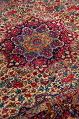 Detalle del medallón central de alfombra persa floral en tonos beige, rojo, azul y dorado