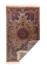 Alfombra persa rectangular doblada con flecos y diseño floral tradicional en tonos beige
