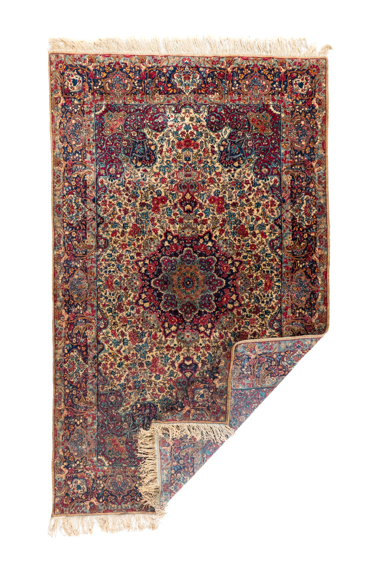 Alfombra persa rectangular doblada con flecos y diseño floral tradicional en tonos beige