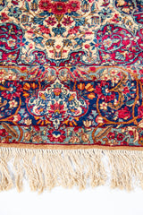 Detalle de guarda y flecos de alfombra persa rectangular con motivos florales multicolor